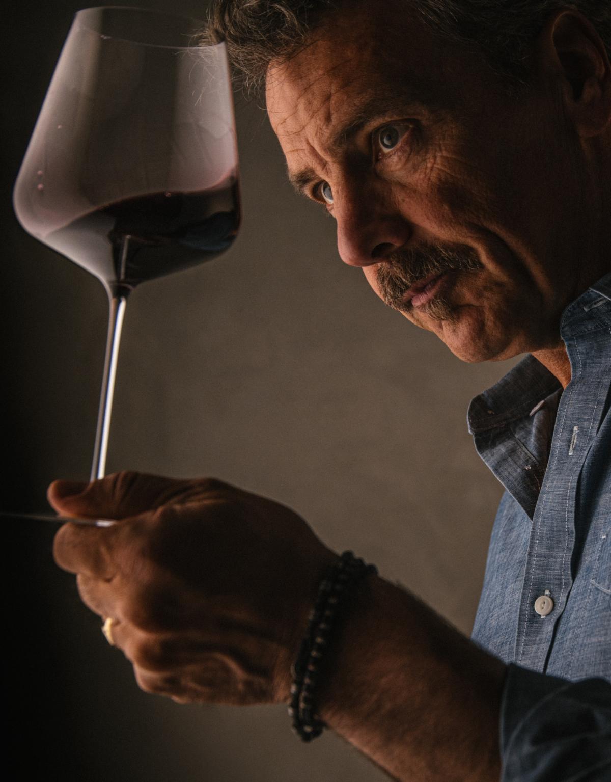 Winemaker Chris Carpenter looking closely at wine glass filled with Caladan wine.